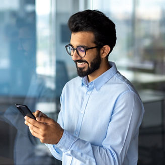 Young successful mature businessman inside the office using the phone, man holding a smartphone online application user, smiling browsing the internet and dialing a call.