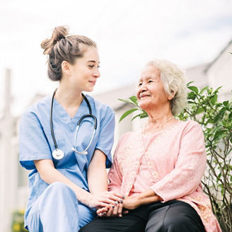 Smiling nurse caregiver holding hand of happy Asian elderly woman outdoor in the park