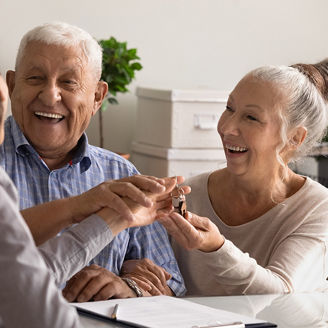 Frau die älterem Paar Schlüssel überreicht