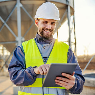 An industry worker working on tablet and checking on supply of silos.