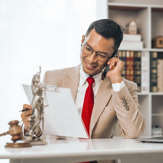 Middle-aged Asian indian people male lawyer meticulously reviews legal documents. Courtroom judge hammer and goddess scales. Depicting the essence of legal counseling and comprehensive services.