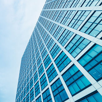 Vista debaixo para cima de um edificio com vários janelões e no fundo o céu azul