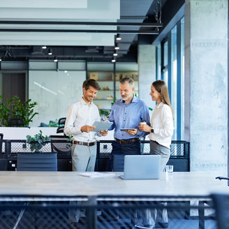 Group of business people standing together and discussing their work and projects, having a team meeting in an office