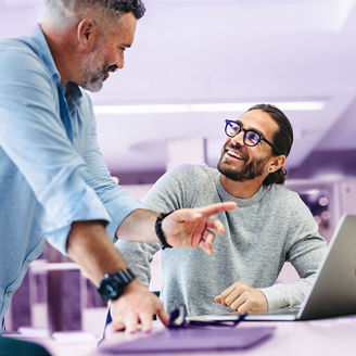 succesvolle man laat trots zijn werk zien op de laptop aan zijn collega