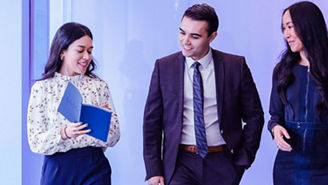 Three colleagues discussing work while walking