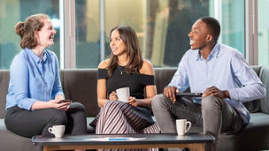 Thre people in discussion whilst sitting down on a sofa