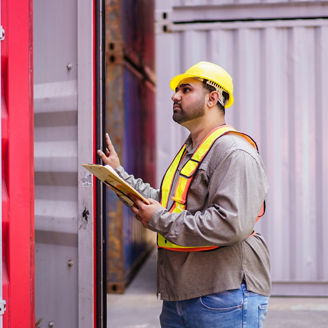 Asian male logistic worker in safety workwear portrait at the container yard. Logistic foreman portrait. Male logistic supervisor is inspecting the incoming cargo container at container yard.