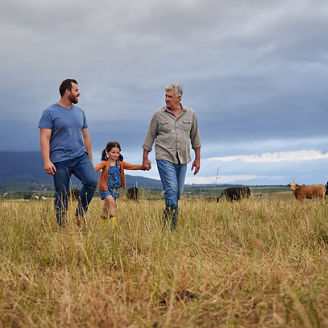 Farmer family walking on a cattle or livestock farm teaching and learning together. Generations of a happy father, grandfather and grandchild bonding on sustainability agriculture land.