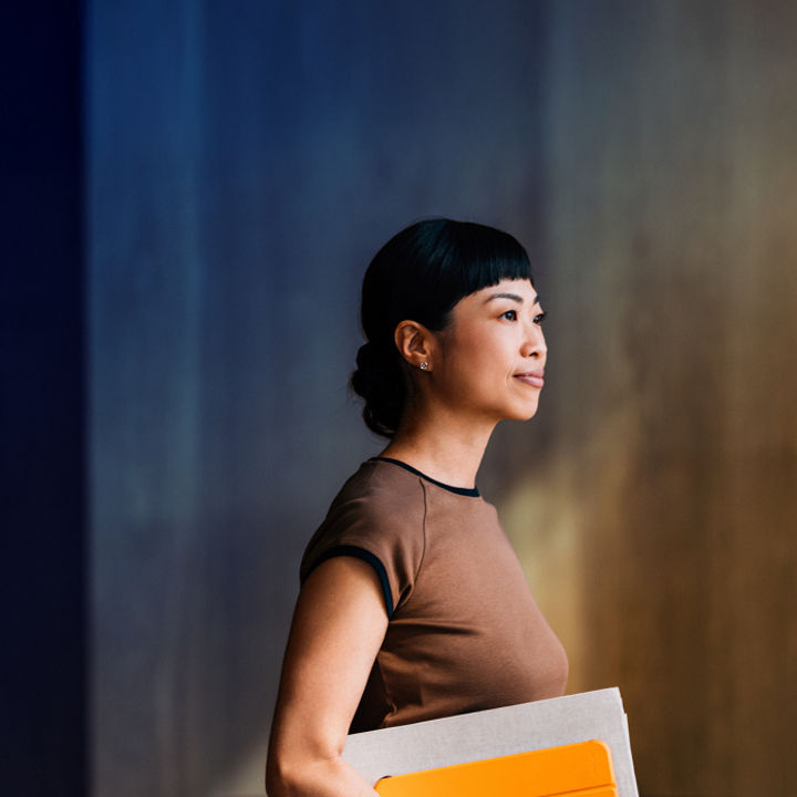A person walking whilst holding various documents