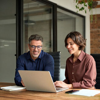 Two collegues looking into laptop at office