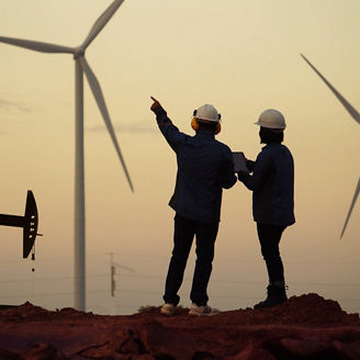 Two construction workers pointing towards windmill