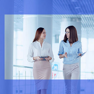 Two female coworkers discussing and walking banner