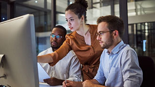 Two man and a woman looking at desktop