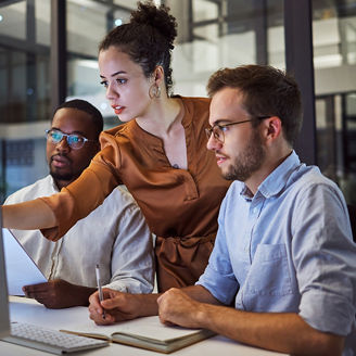 Two man and a woman looking at desktop