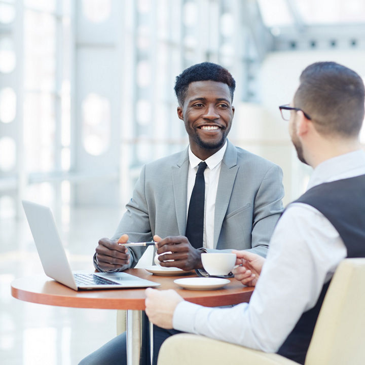 Portrait of successful African-American businessman smiling during meeting with colleague at coffee break