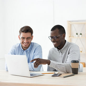 Two men smiling looking at laptop screen