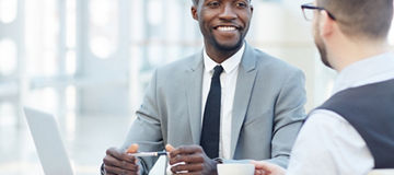Portrait of successful African-American businessman smiling during meeting with colleague at coffee break