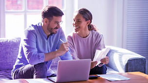 Two people talking with laptop and calculator on table