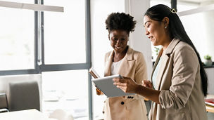 two women looking at tab and talking