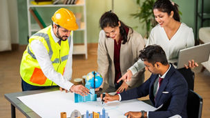 Indian asian Architect, builder and engineer meeting together and discussing city planning on table