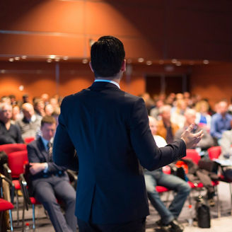 The speaker gives a business presentation to a group of people.