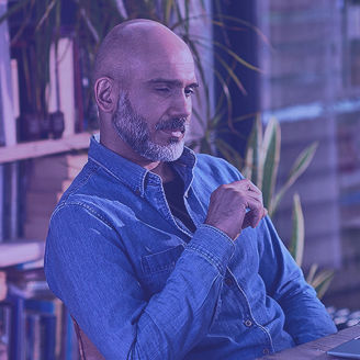Mann sitzt vorm Bücherregal