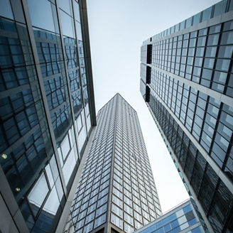 A vertical low angle shot of high rise skyscrapers in a glass facade in Frankfurt, Germany