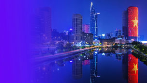 Vietnam city skyline with illuminated high‑rise buildings reflected in a river, featuring a purple gradient overlay along the left side of the image