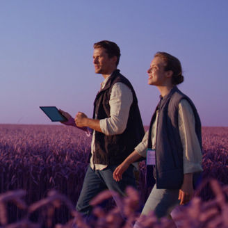 Man en vrouw lopen in een veld met hun tablat in hun hand.