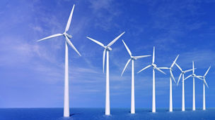 White wind mill in sea against clear blue sky