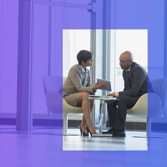 Two people sit at a small table and talk to each other