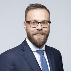 Porträt von Wolfgang Gurtner vor einer hellgrauen Wand