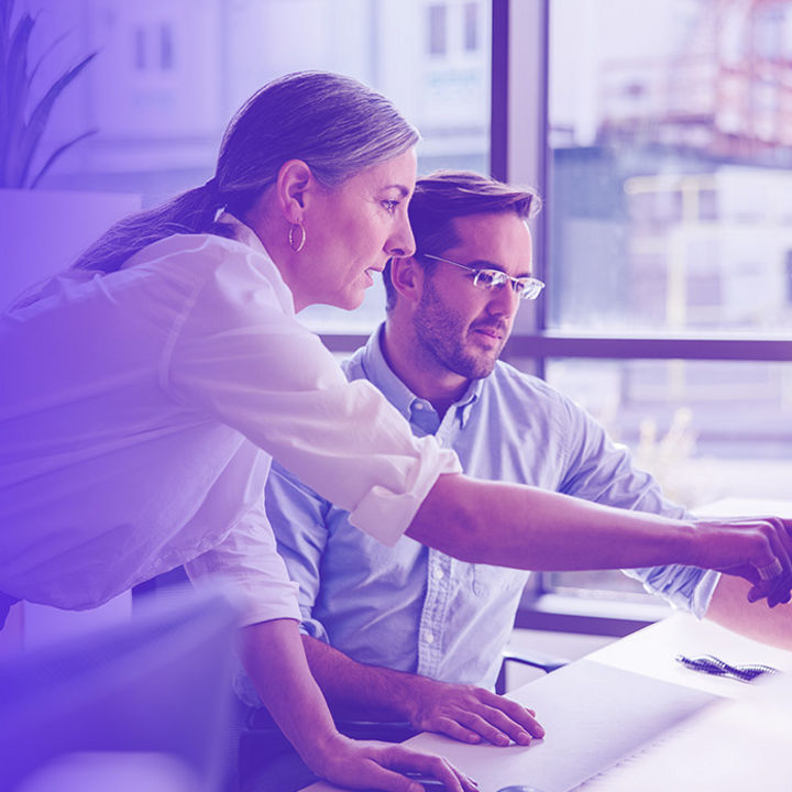 A woman and a man pointing at a computer screen in office