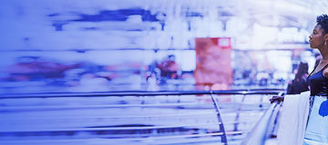 A beautiful young elegant black woman is standing next to the railing of a modern shopping mall with disposable paper bags with purchases in her hand after shopping; a copy space place on the right