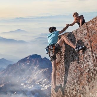 Woman helping man climbing mountain