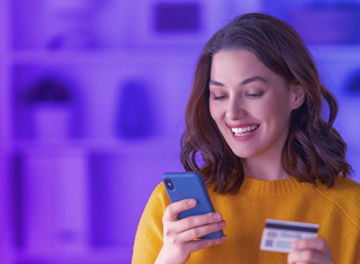 Person looking at her phone with a bank card