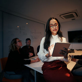 Woman looking into tab in a meeting room.