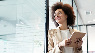 woman looking out the window with a tablet in her hand