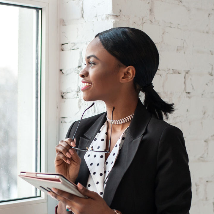 Woman looking out of a window with a tablet in her hand
