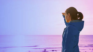 Woman on the beach looking at the sun banner