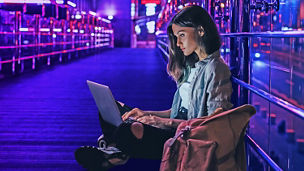 vrouw aan het werk met laptop op haar schoot en lichten op de achtgergrond