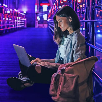 vrouw aan het werk met laptop op haar schoot en lichten op de achtgergrond