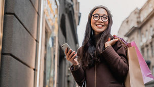 Woman using smartphone and looking away while enjoying a day shopping