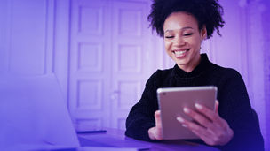 Happy female student freelancer laughs while working on a computer gadget