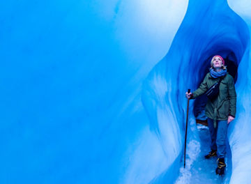 Woman standing in an ice cave looking up to the light
