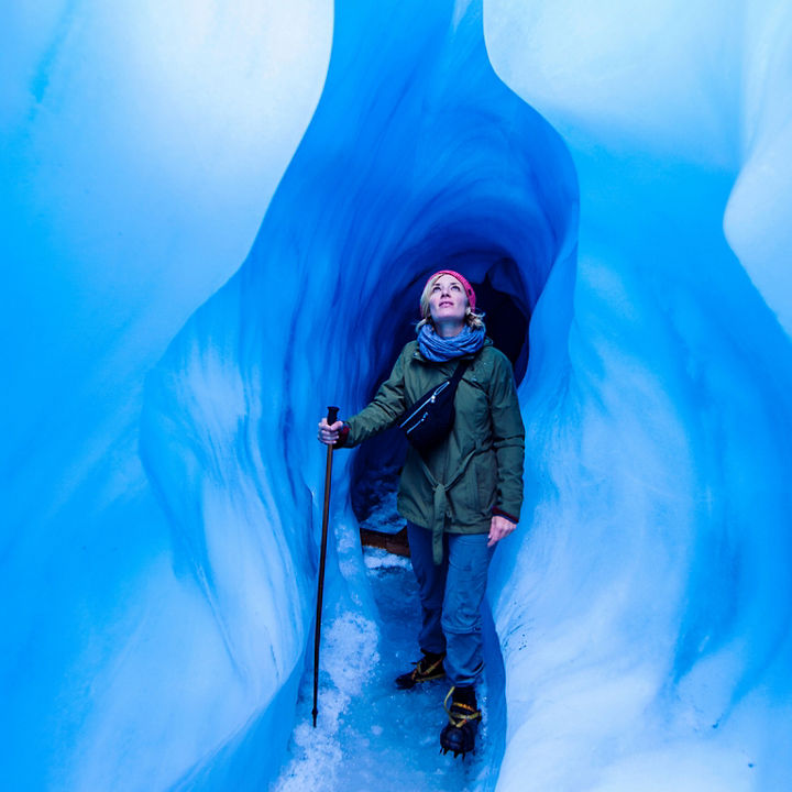Woman standing in an ice cave looking up to the light