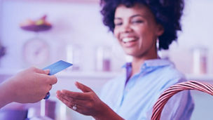 Shot of a female juice bar owner taking payment from customer. Female customer paying for juice with credit card.