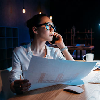 Woman talking on the phone and looking at her laptop while working