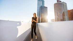 Woman walking on footbridge with glass buildings in background