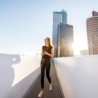 Woman walking on footbridge with glass buildings in background